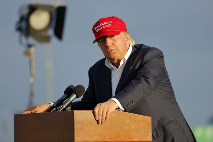 SAN PEDRO, CA - SEPTEMBER 15, 2015: Donald Trump, 2016 Republican presidential candidate, speaks during a rally aboard the Battleship USS Iowa in San Pedro, Los Angeles, California while wearing a red baseball hat that says campaign slogan Make America Great Again.